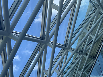 Interior of glass roof of Faculty building with blue sky showing.